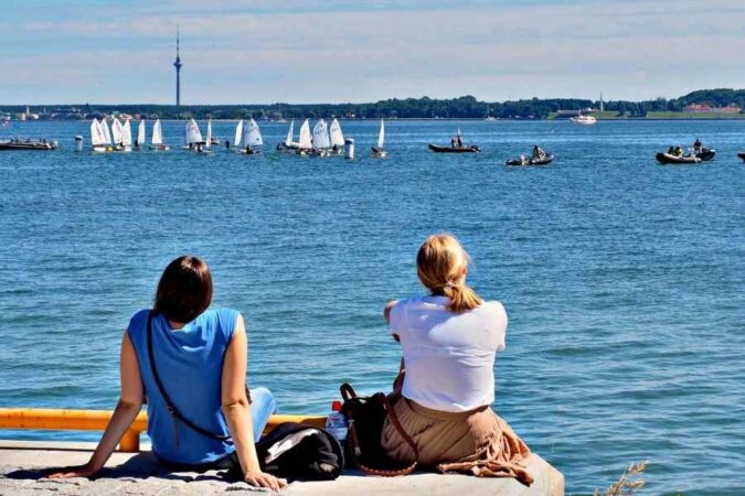 Deux amies profitent d'un week-end au bord de la mer en observant des voiliers sur l'eau.